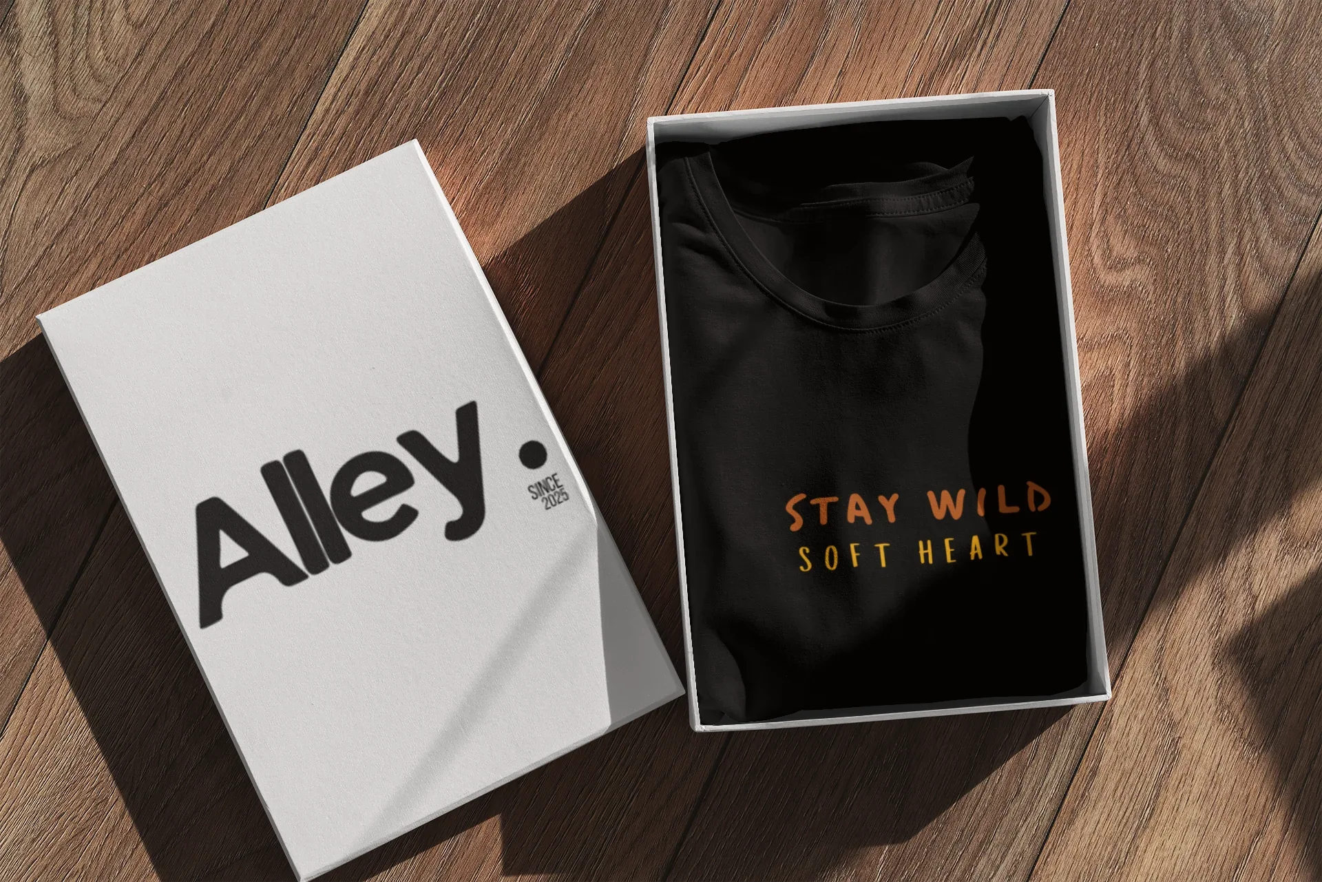 Black hoodie laid in open box, showing Wild West emblem and Stay Wild Soft Heart text