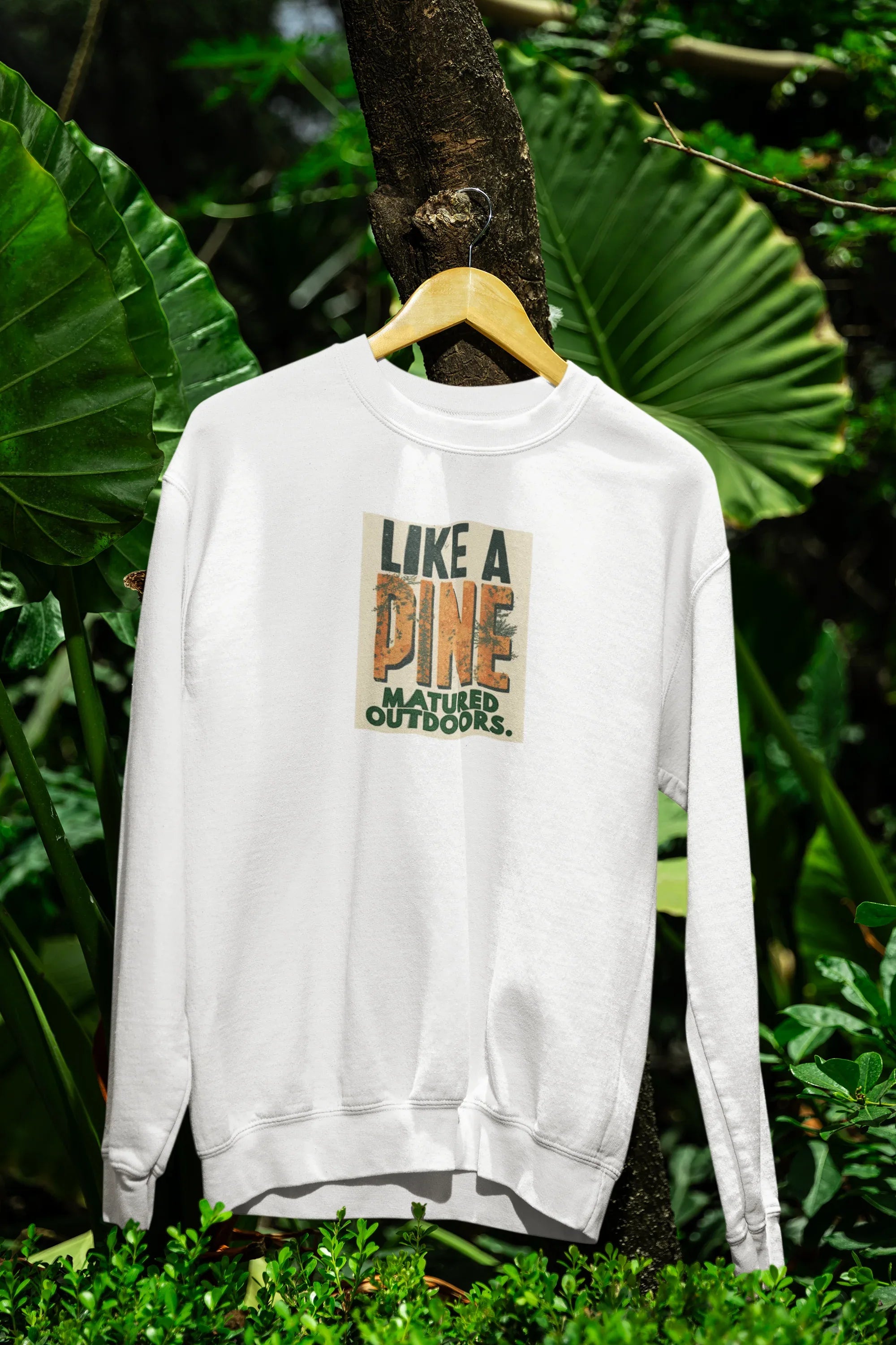 White crewneck sweatshirt with front graphic logo, on a wooden hanger