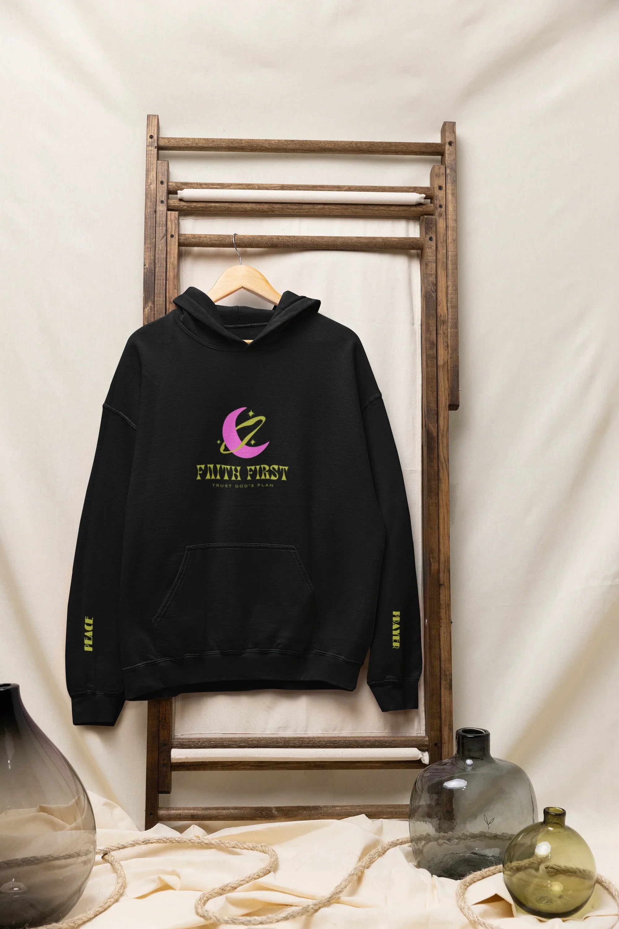 Black unisex hoodie on rack with front Faith First logo and crescent graphic