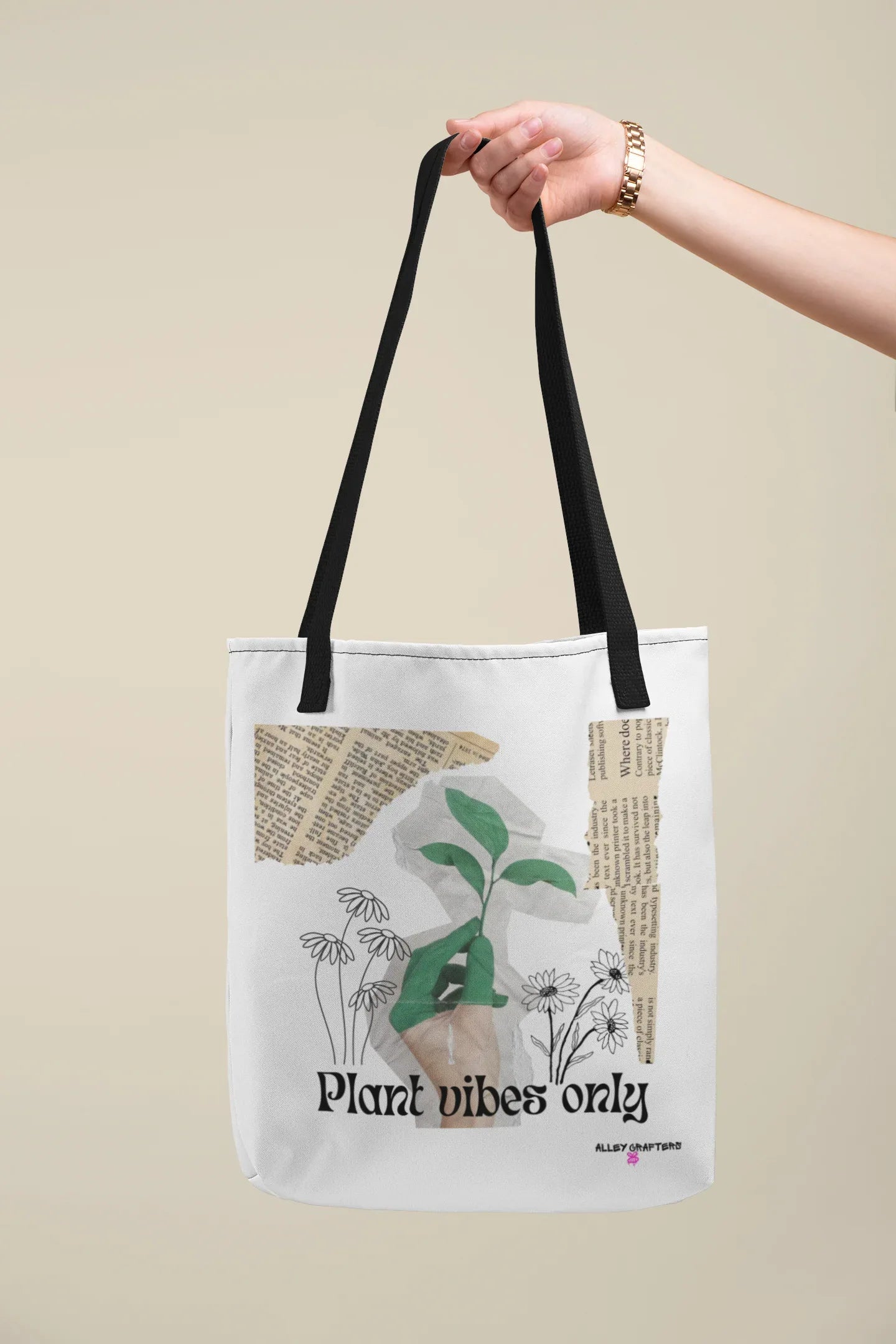 White tote bag with black handles and green plant graphic, held overhead