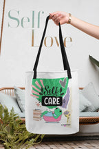 White tote bag with black handles featuring “Self Care” and green frog artwork