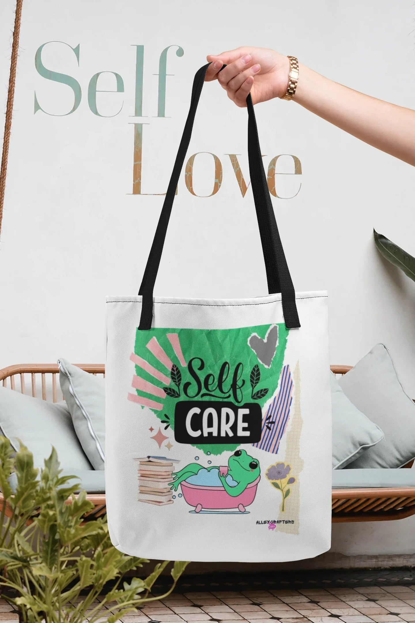 White tote bag with black handles featuring “Self Care” and green frog artwork