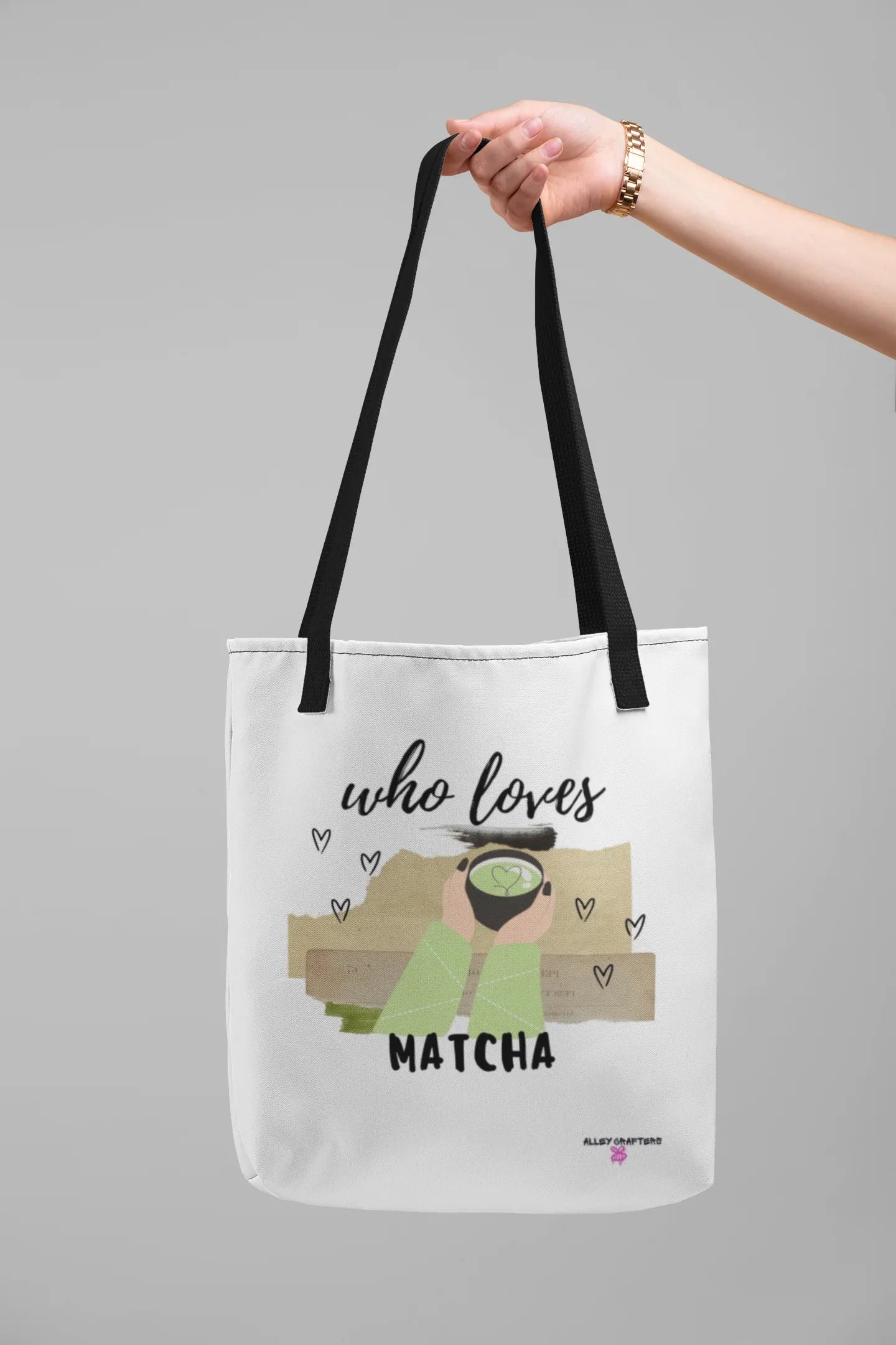 White tote bag with “who loves MATCHA” graphic, shown front view with black handles.