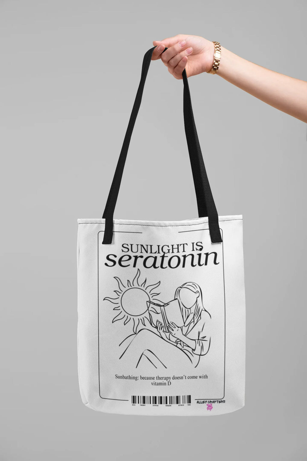 White canvas tote bag held by handles, showing black front text and illustration