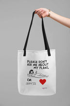 White canvas tote bag with black handles and “Please don’t ask me about my plans” quote