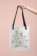 White canvas tote bag with black handle straps, botanical print, and cursive "Sophie"