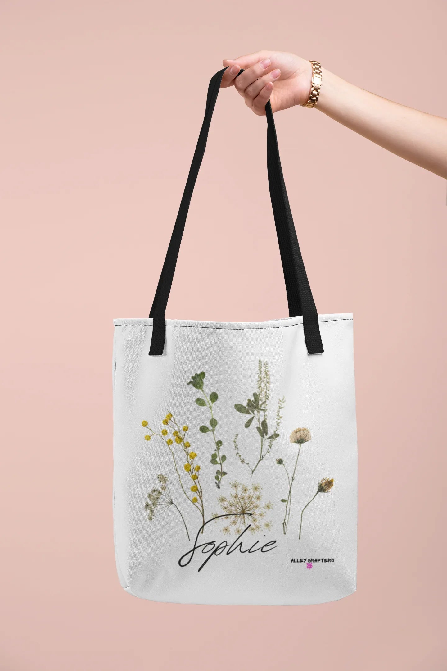 White canvas tote bag with black handle straps, botanical print, and cursive "Sophie"