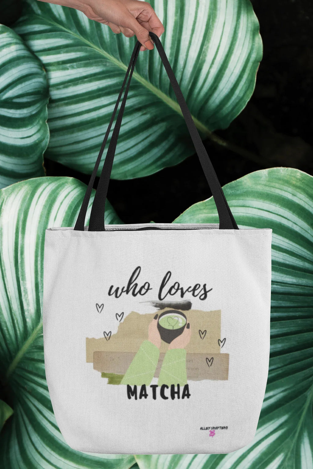 White tote bag held over green striped fabric, with “who loves MATCHA” graphic.