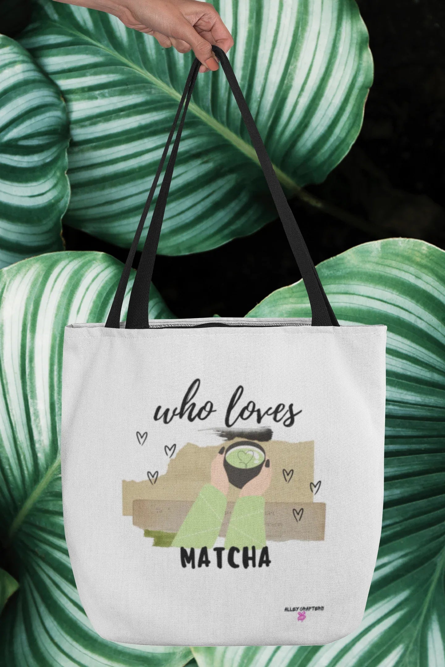White tote bag held over green striped fabric, with “who loves MATCHA” graphic.