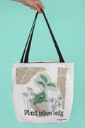 Black-handled white tote bag with green plant graphic and 'Plant vibes only' text