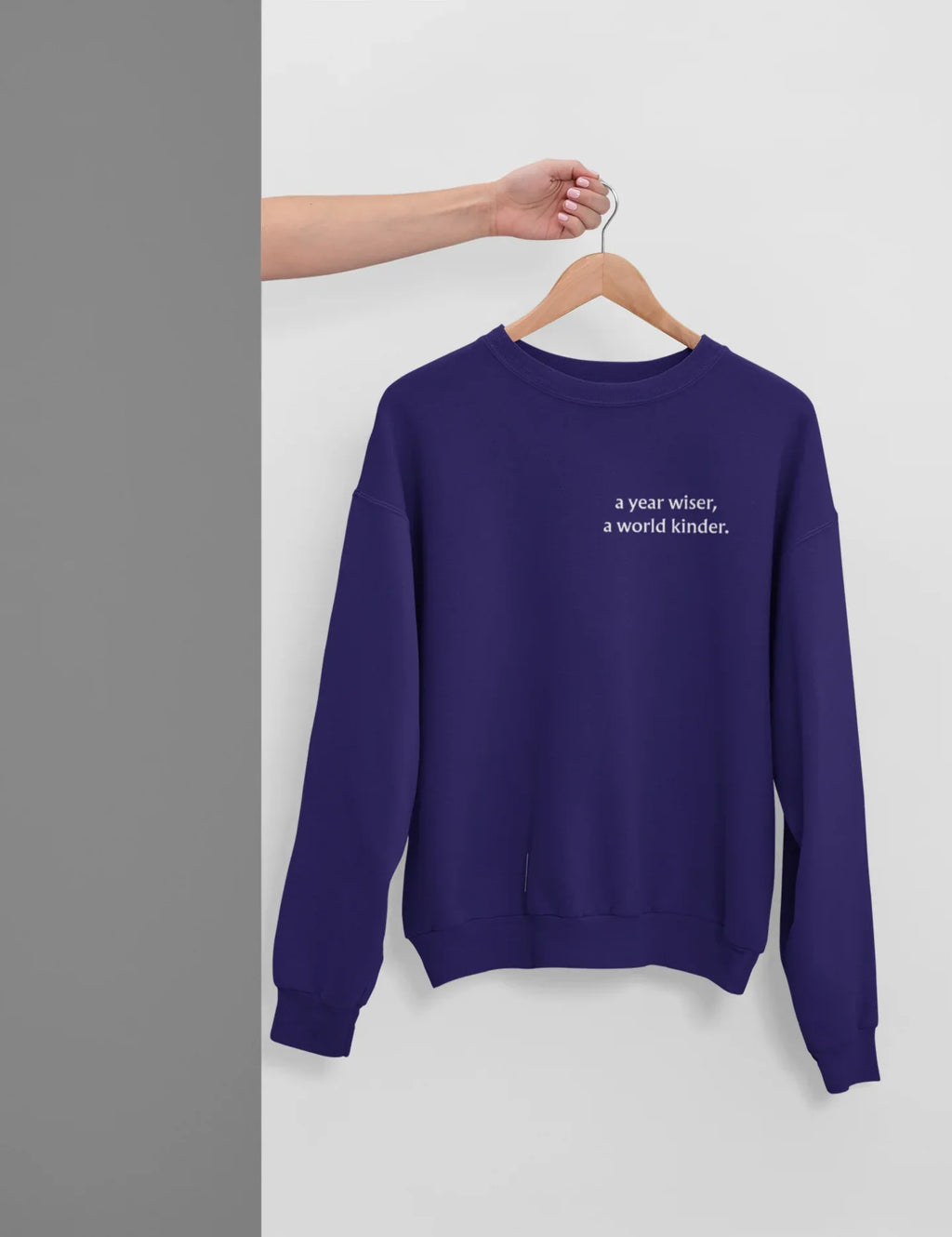 Purple crewneck sweatshirt with 'a year wiser, a world kinder.' print