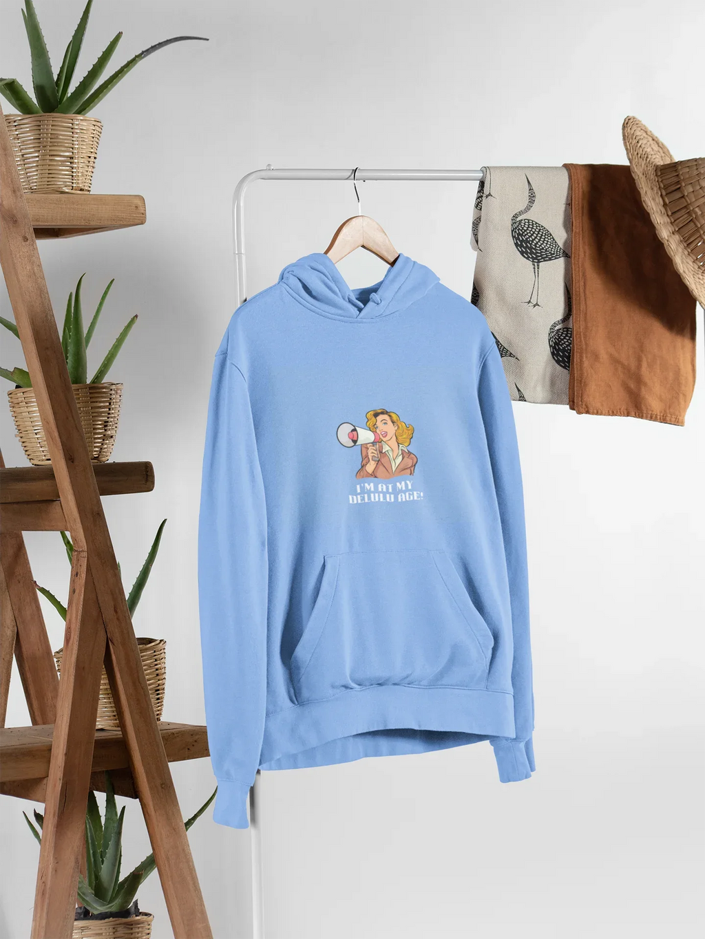 Light blue hooded sweatshirt hanging, with front pocket and chest graphic