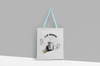 White canvas tote bag with light blue handles and Stay Grounded coffee cup graphic