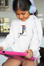 White kids hoodie on a child wearing headphones, floral letter and script name on chest