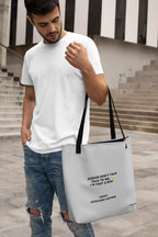 White tote bag with black handles and printed slogan on front