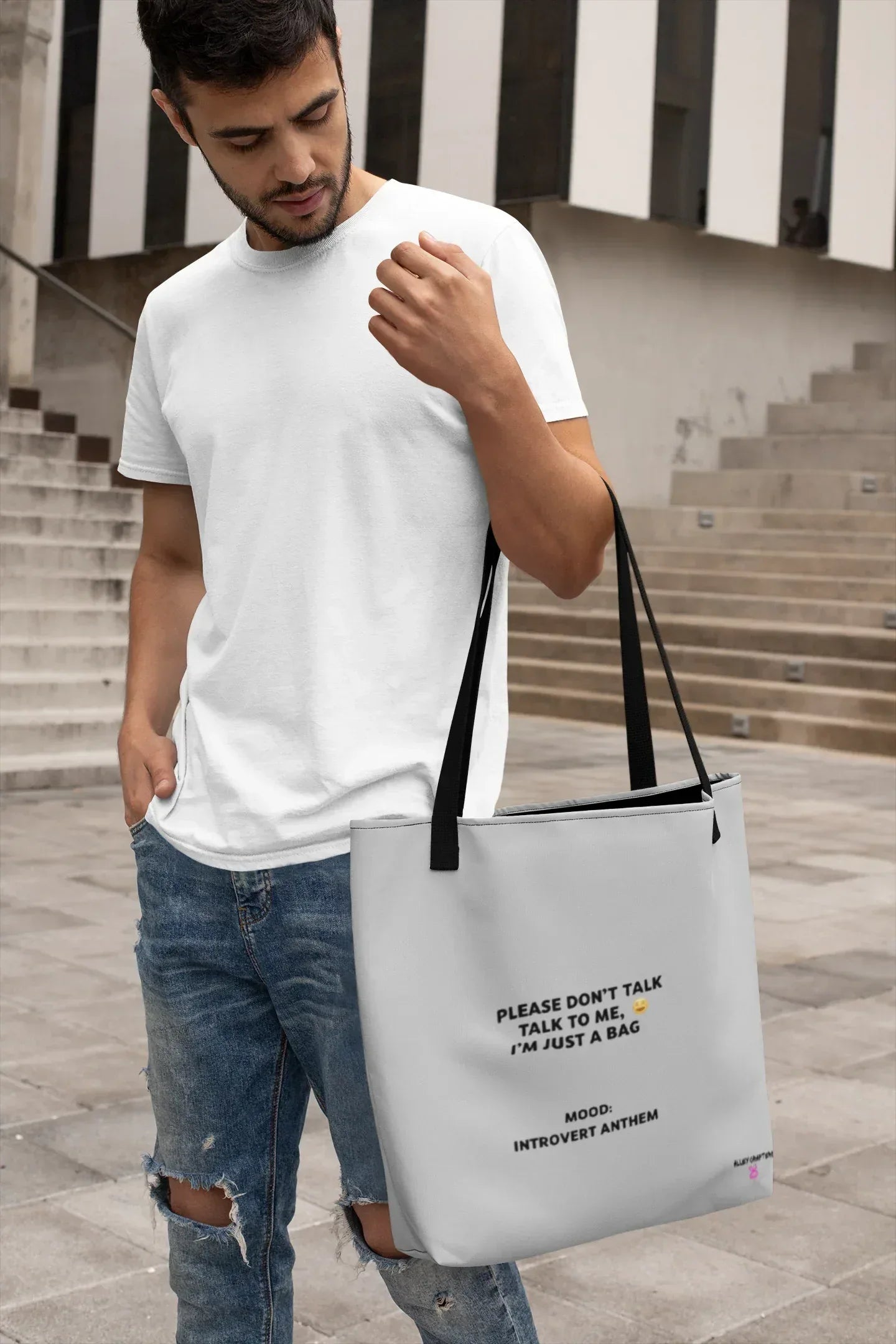 White tote bag with black handles and printed slogan on front