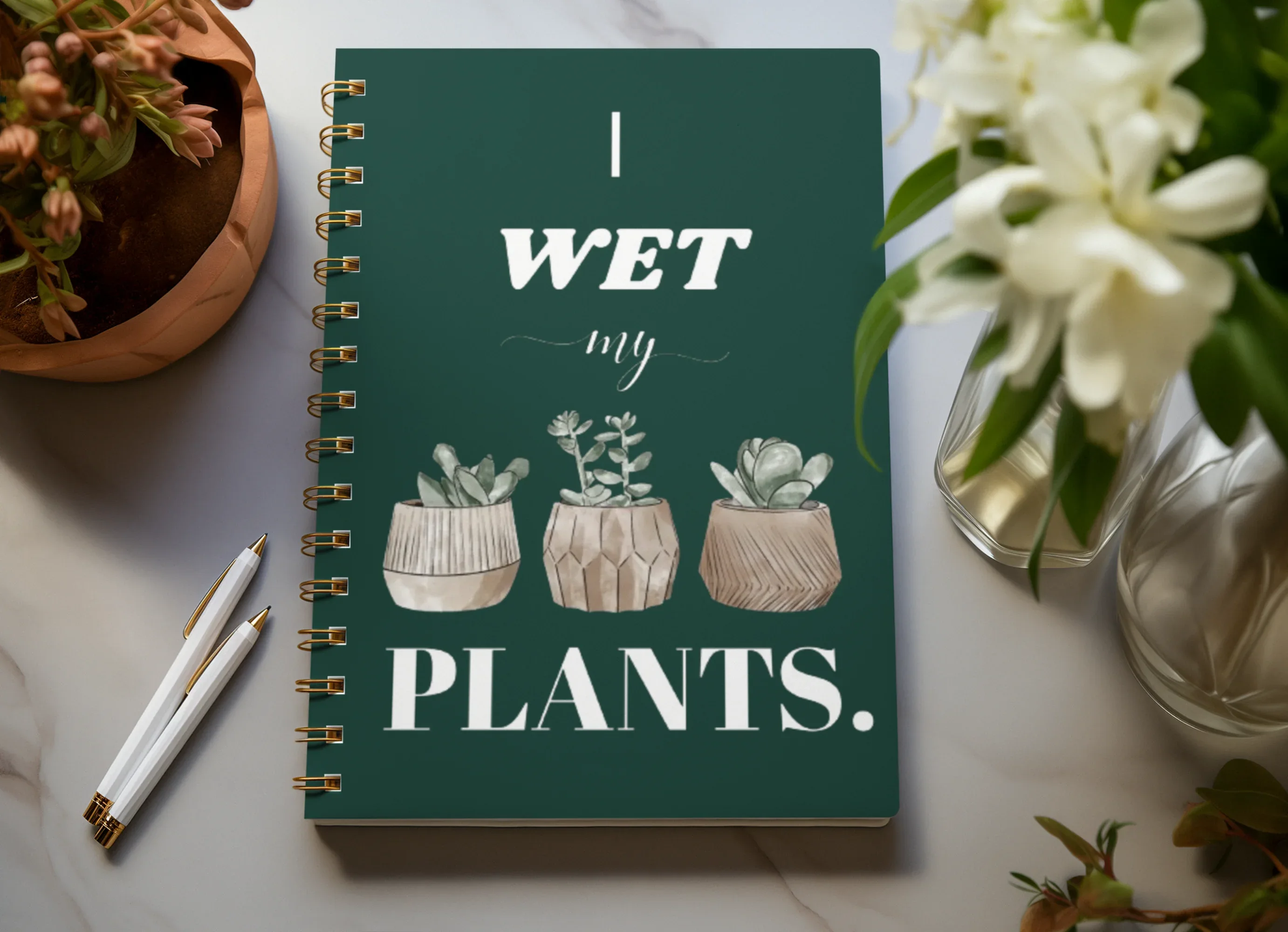 A5 spiral notebook, dark teal cover with “I wet my plants” text and succulent pot artwork.