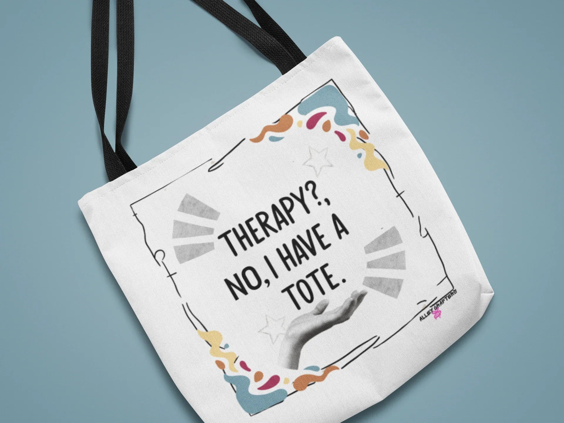 White tote bag with black text print and colorful confetti-style border, dark handles