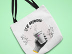 White canvas tote bag with black handles and Stay Grounded coffee cup graphic close-up