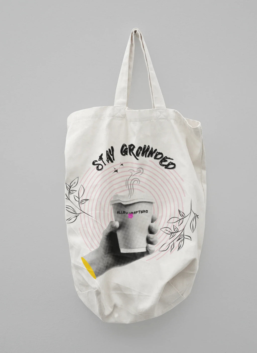 White canvas tote bag with beige handles and Stay Grounded coffee cup graphic