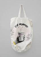 White canvas tote bag with beige handles and Stay Grounded coffee cup graphic