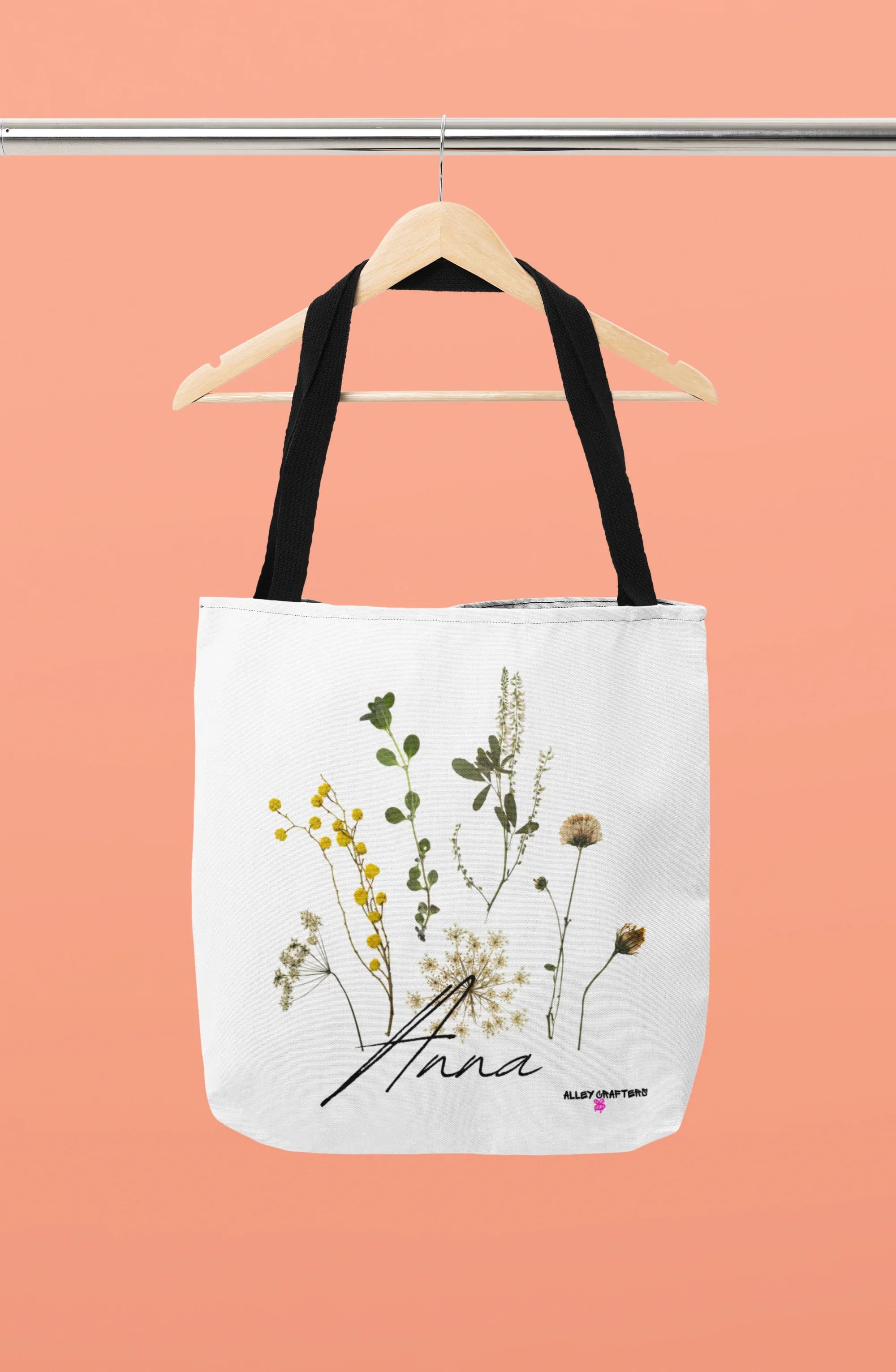 White canvas tote bag with black handle straps and botanical flower print front