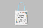 White tote bag with “Therapy?, No, I have a Tote” print and colorful border, light blue handles