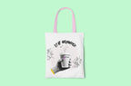 White canvas tote bag with pink handles and Stay Grounded coffee cup graphic