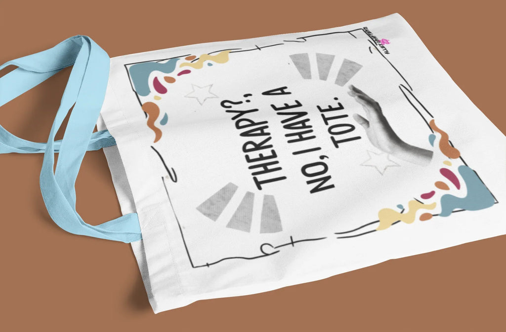 White tote bag with “Therapy?, No, I have a Tote” text and colorful border, light strap