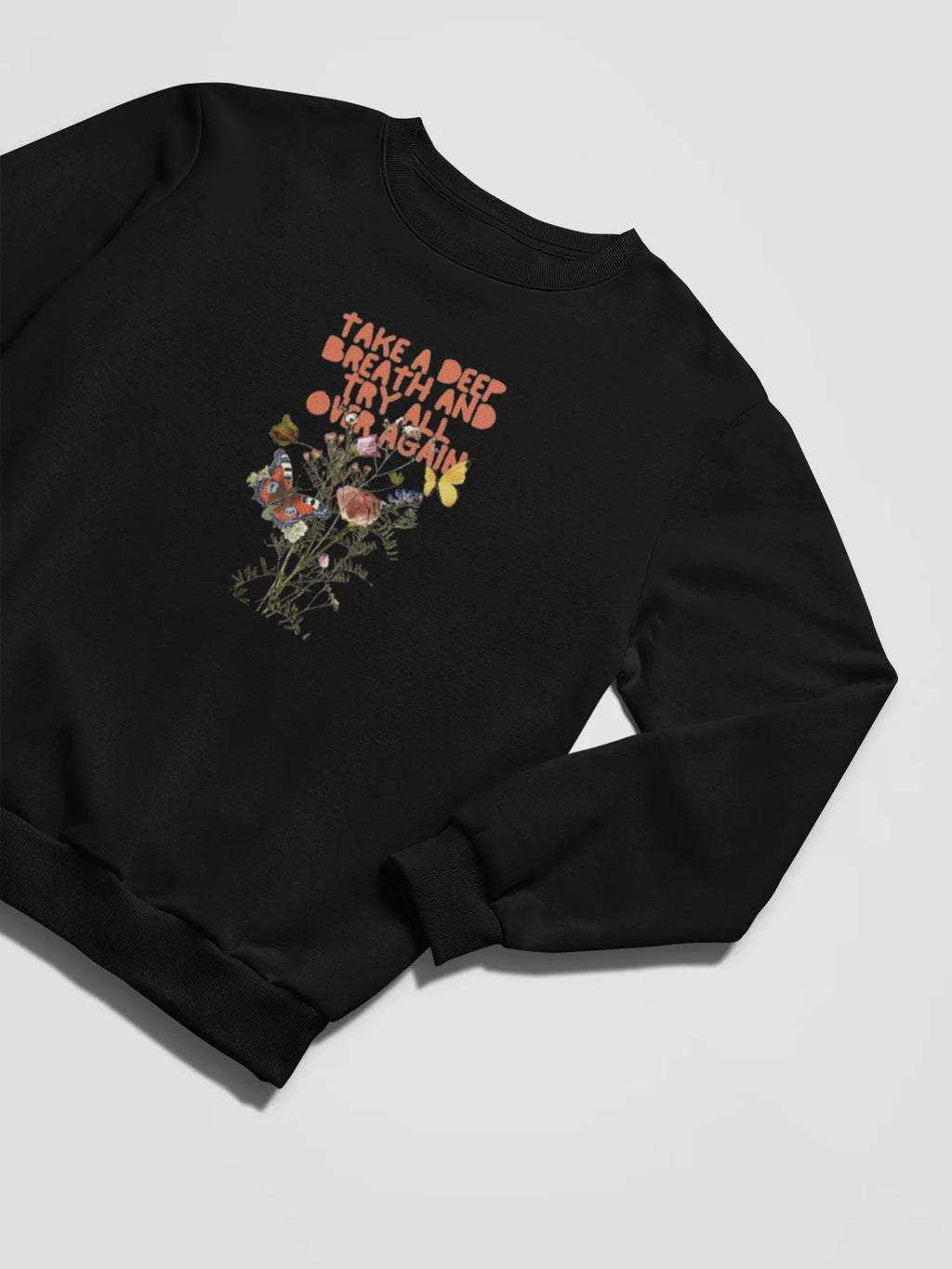 Black crewneck sweatshirt with small floral graphic and inspirational text on chest