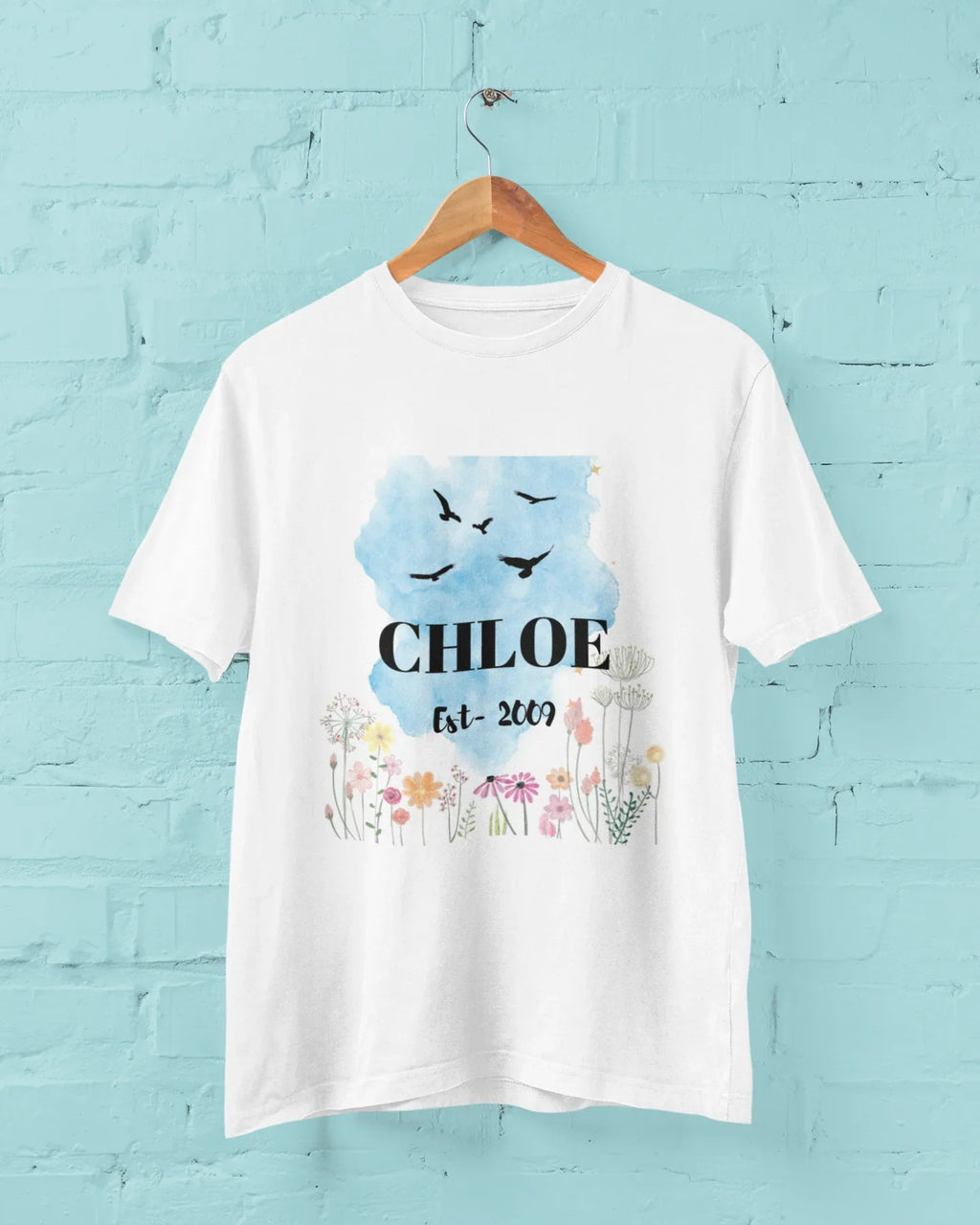 Hanging white T-shirt, blue birds and floral design with name and year.