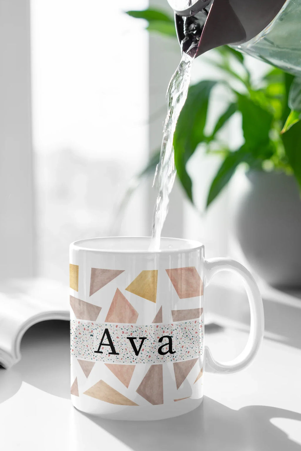 White mug with geometric triangles and name Ava, with liquid pouring inside