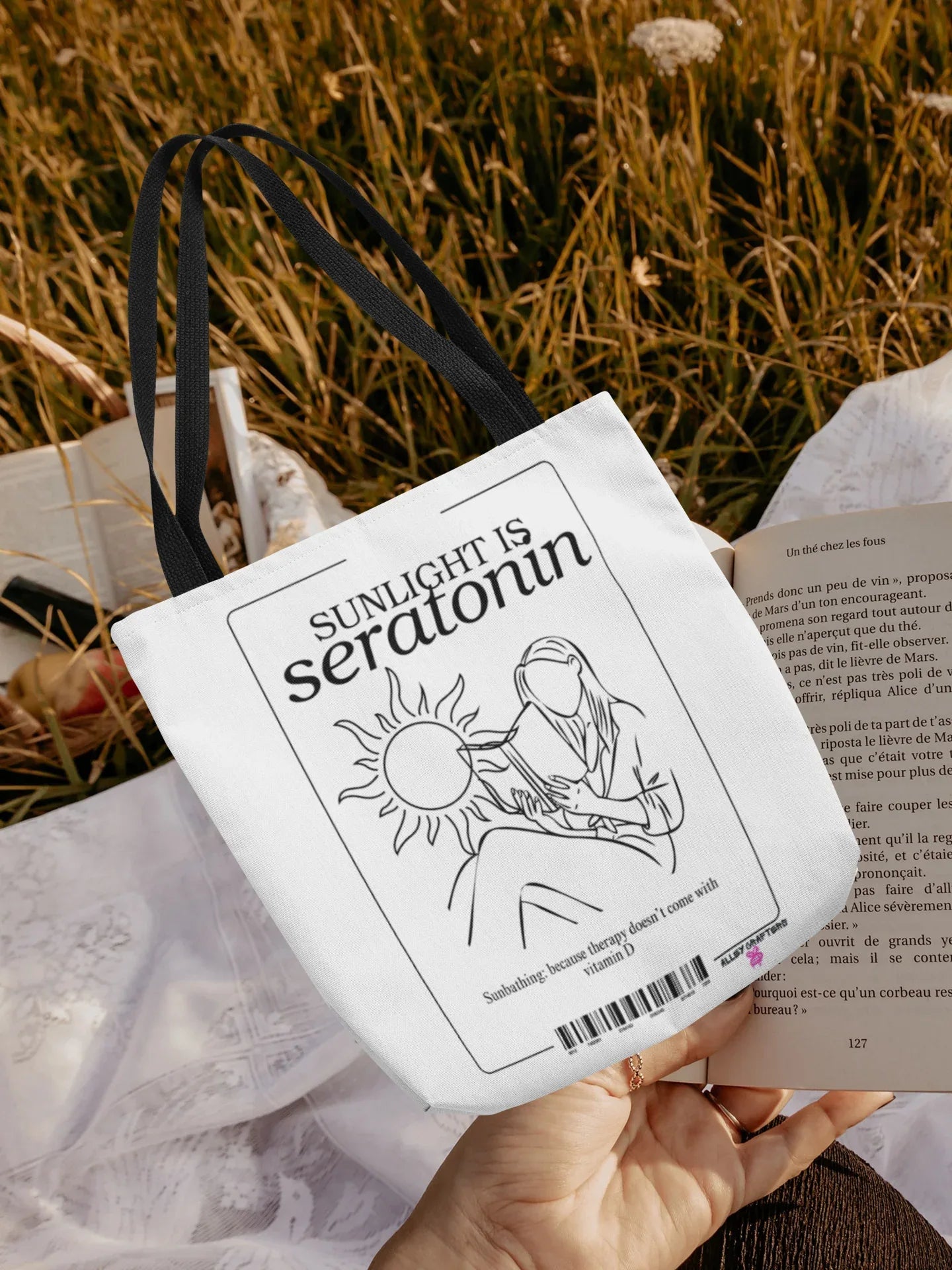 White canvas tote bag close-up in hand, showing black front illustration and barcode