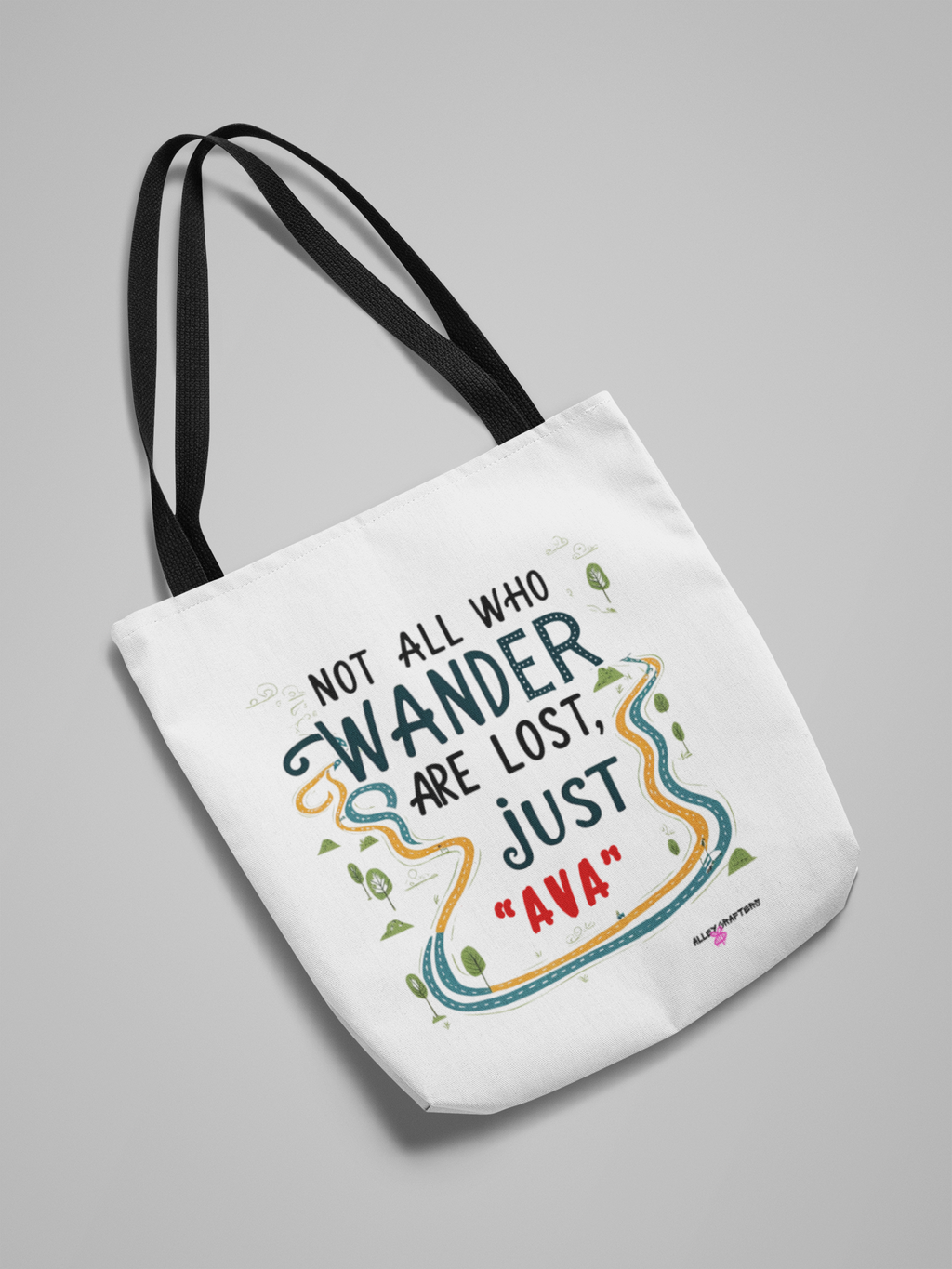 White canvas tote bag with long black handles and colorful “wander” quote on front