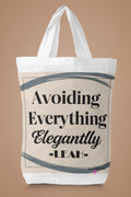 White canvas tote bag with large "Avoiding Everything Elegantly" lettering