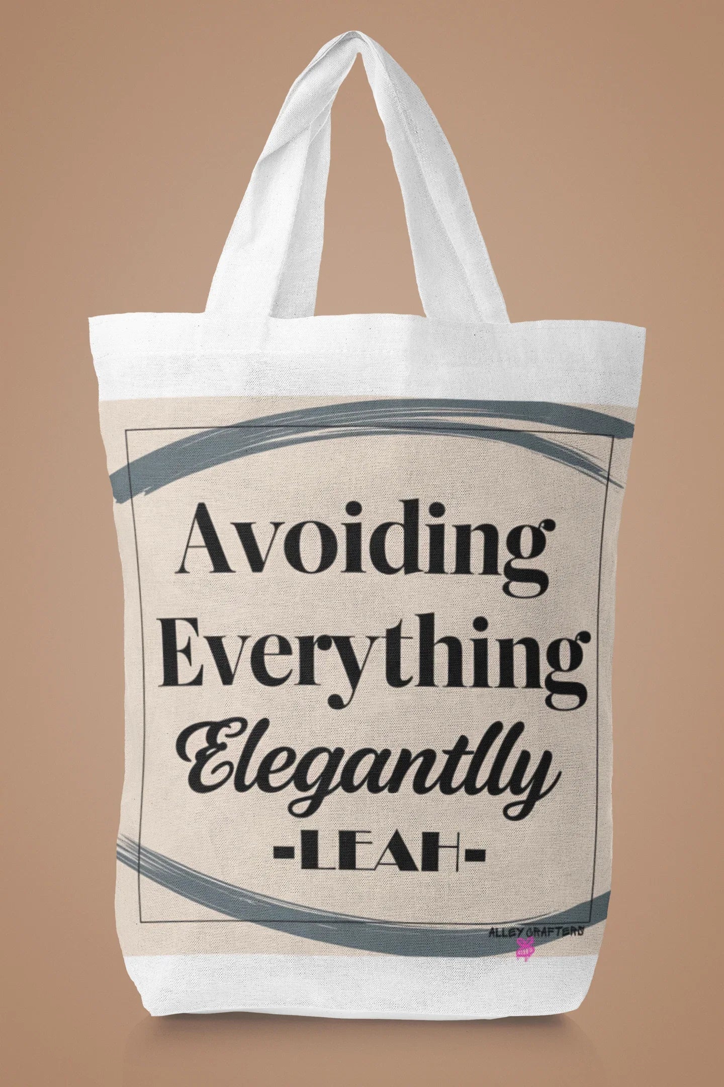 White canvas tote bag with large "Avoiding Everything Elegantly" lettering