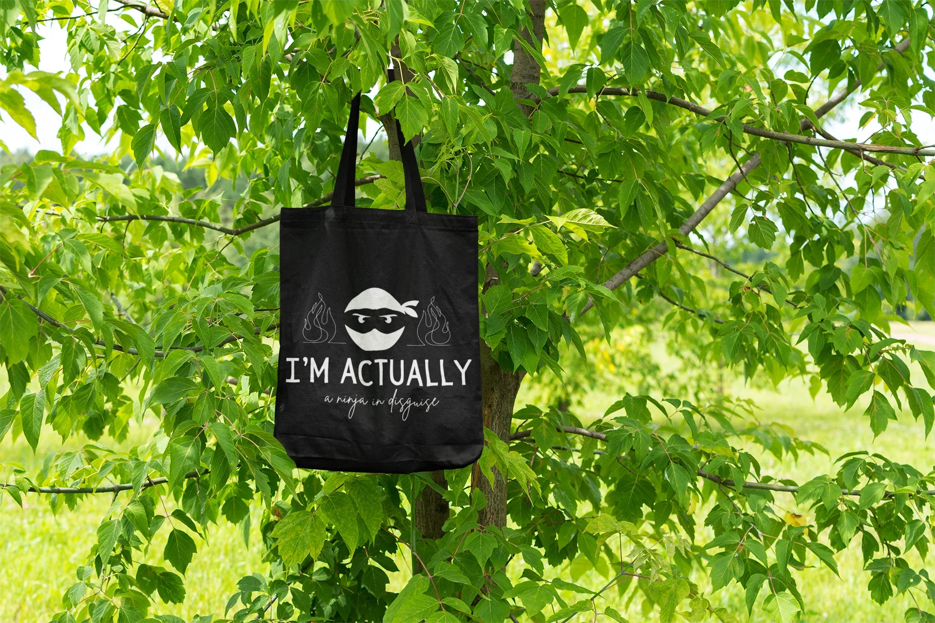 Black tote bag with ninja face logo and 'I'M ACTUALLY' text, 'a ninja in disguise'.