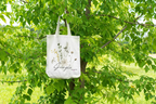 White tote bag with botanical plant print, hanging from short handles