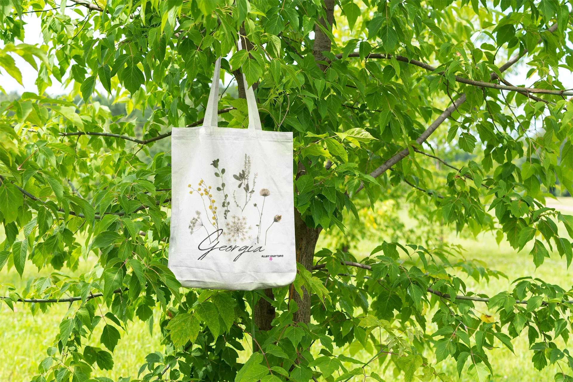 White tote bag with botanical plant print, hanging from short handles