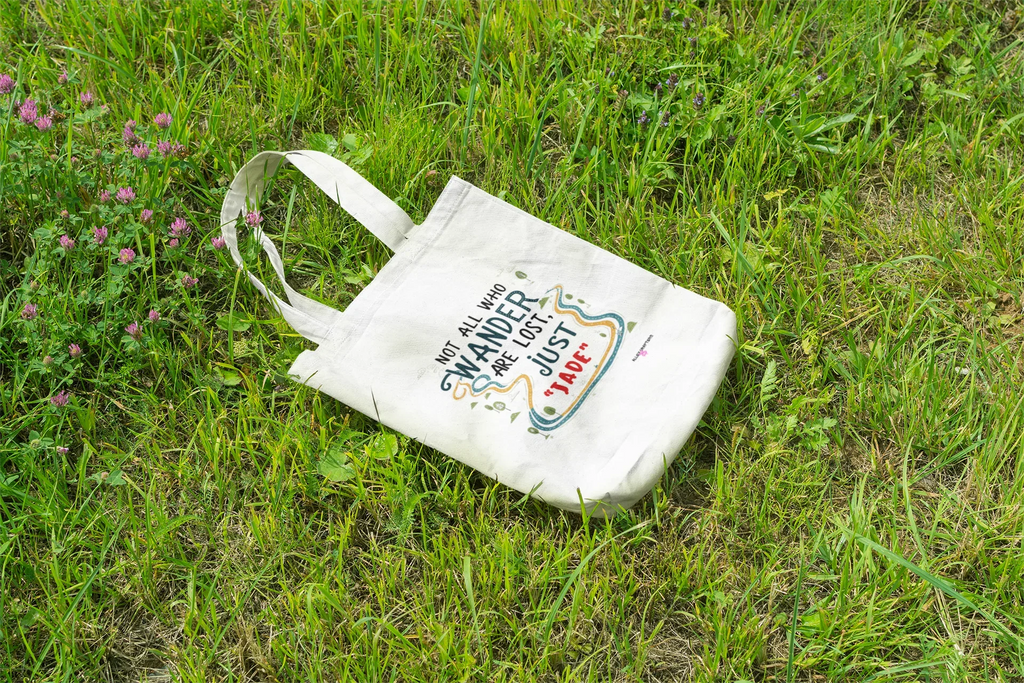 White canvas tote bag lying flat with long handles and colorful front quote graphic