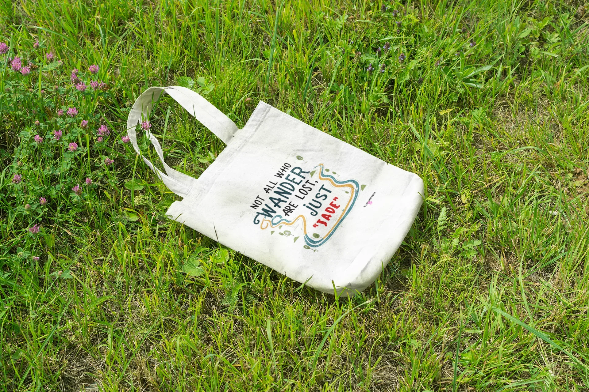 White canvas tote bag lying flat with long handles and colorful front quote graphic