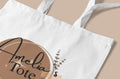 White cotton tote bag with circular “Amelia” print and small botanical sprig