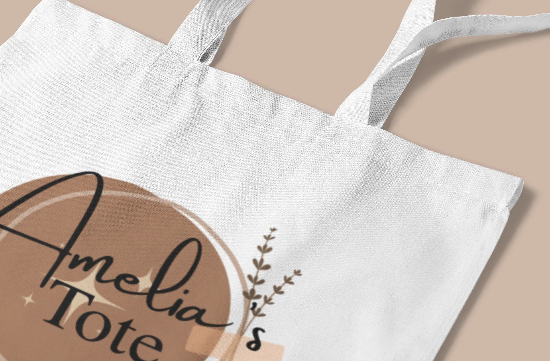 White cotton tote bag with circular “Amelia” print and small botanical sprig