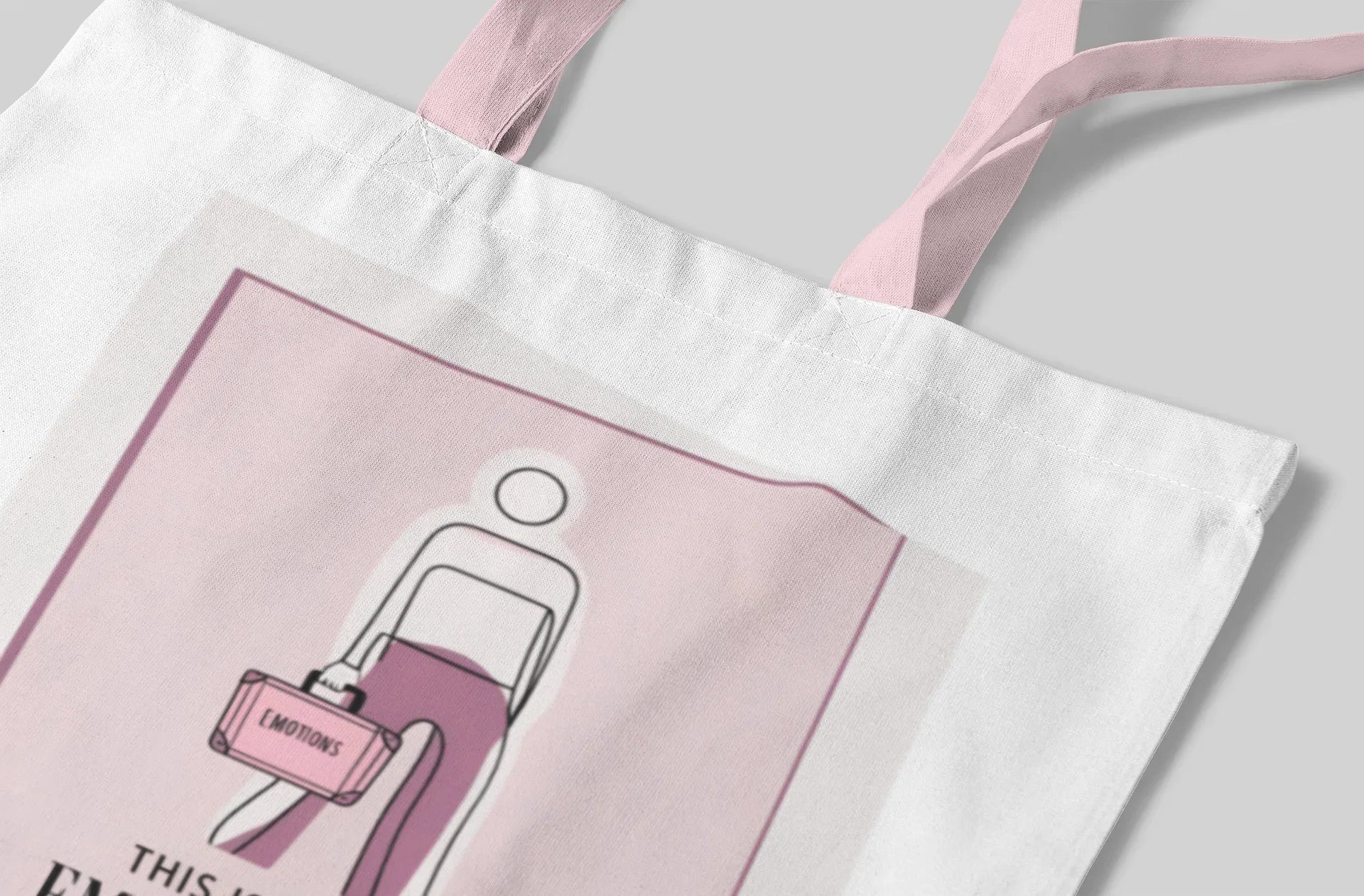 White canvas tote bag close-up of pink graphic panel and handle strap.