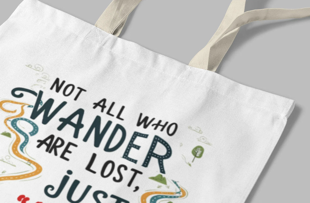 White tote bag close-up showing 'NOT ALL WHO WANDER' text graphic