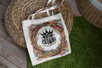 White tote bag with black crown emblem and multicolor scribble wreath