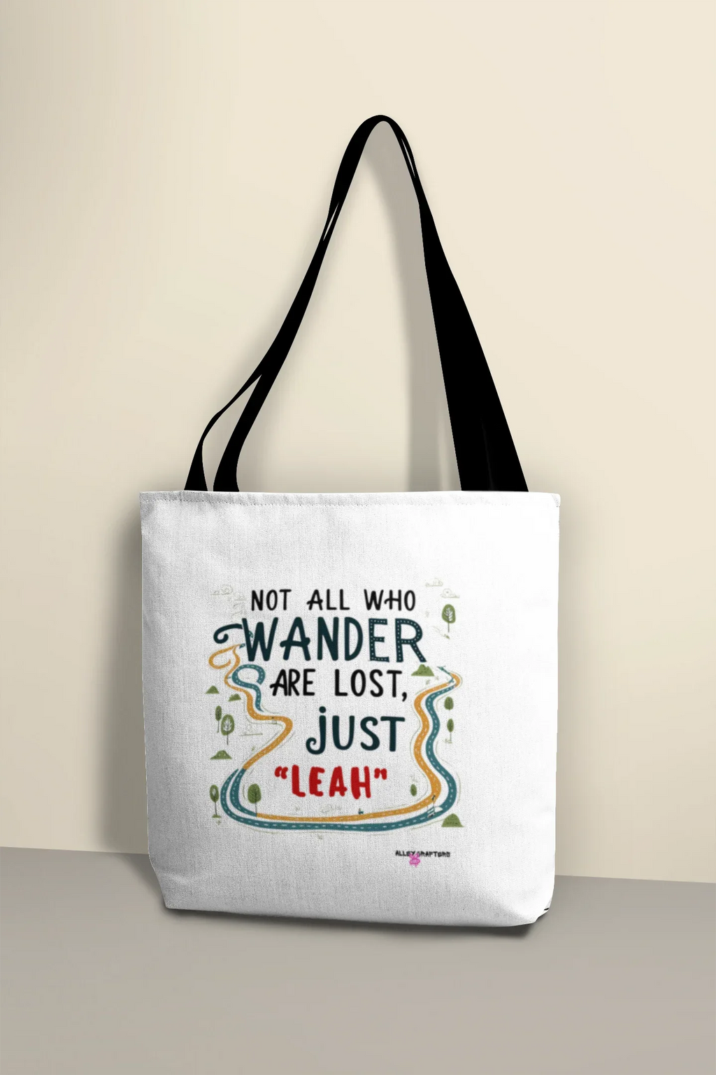 White tote bag with black handles and colorful 'Not all who wander' print