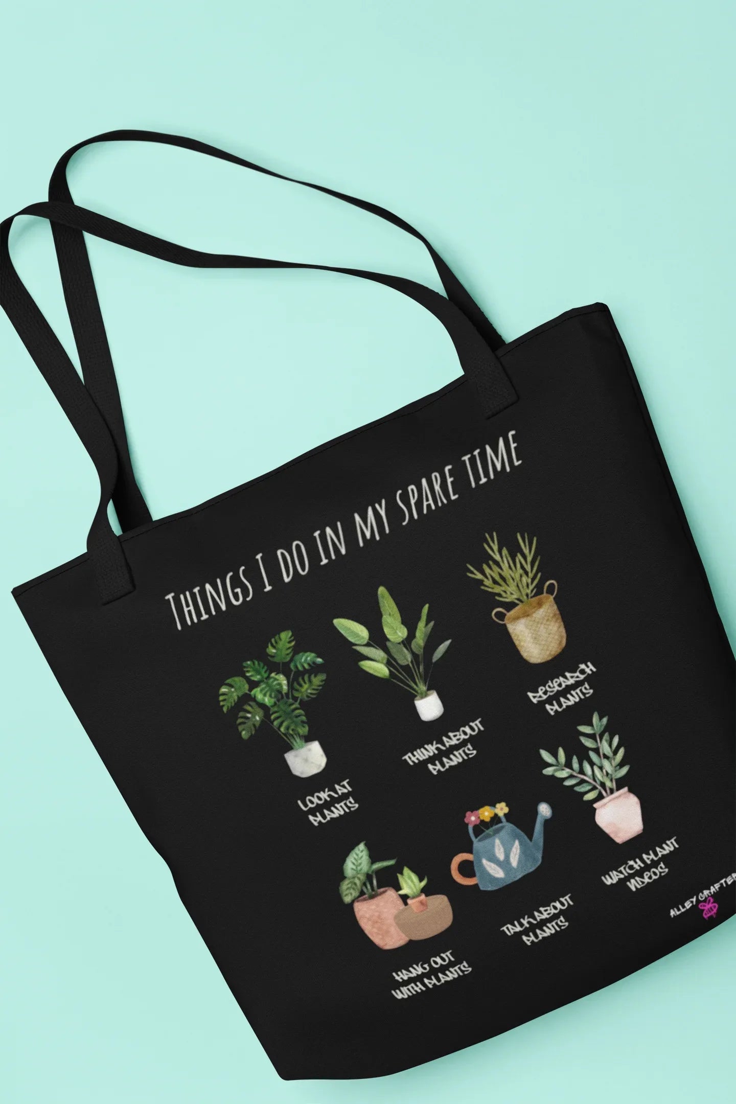 Black tote bag with plant-themed graphic and phrase, wide handles