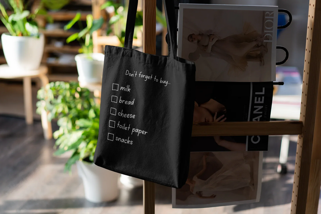 Black grocery tote bag with 'Don't forget to buy' checklist boxes for milk, bread, cheese, snacks.