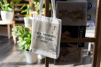 White tote bag hanging on stand, front print 'OVER THINKING EVERYTHING - Pheonix'